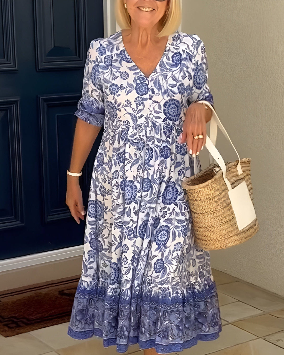 Woman wearing an elegant floral V-neck dress in blue with a flowing silhouette, styled for a warm sunny day