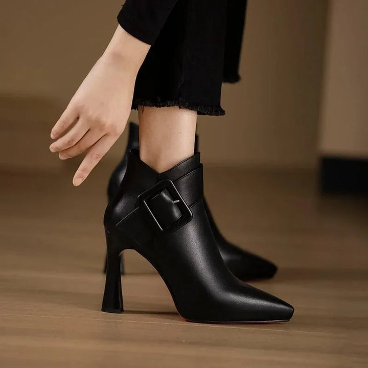 Aveline buckle heel boots in black showing sleek silhouette and buckle detail, side view