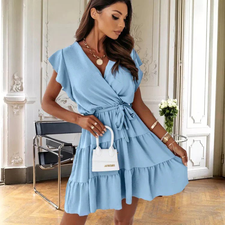 Woman wearing the Blossom blue wrap mini dress with flutter sleeves and self-tie waist belt, front view
