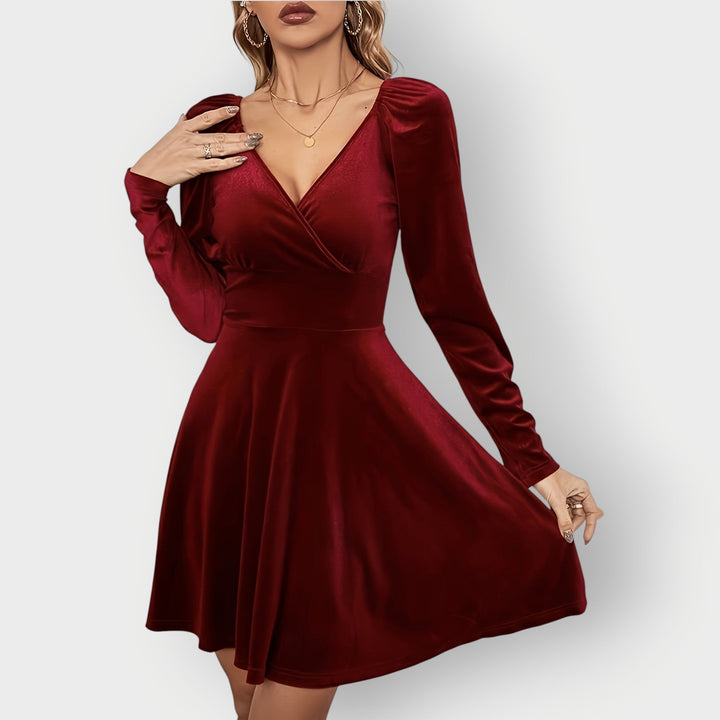 Woman wearing a red velvet skater dress with a fitted bodice and flared skirt, front view
