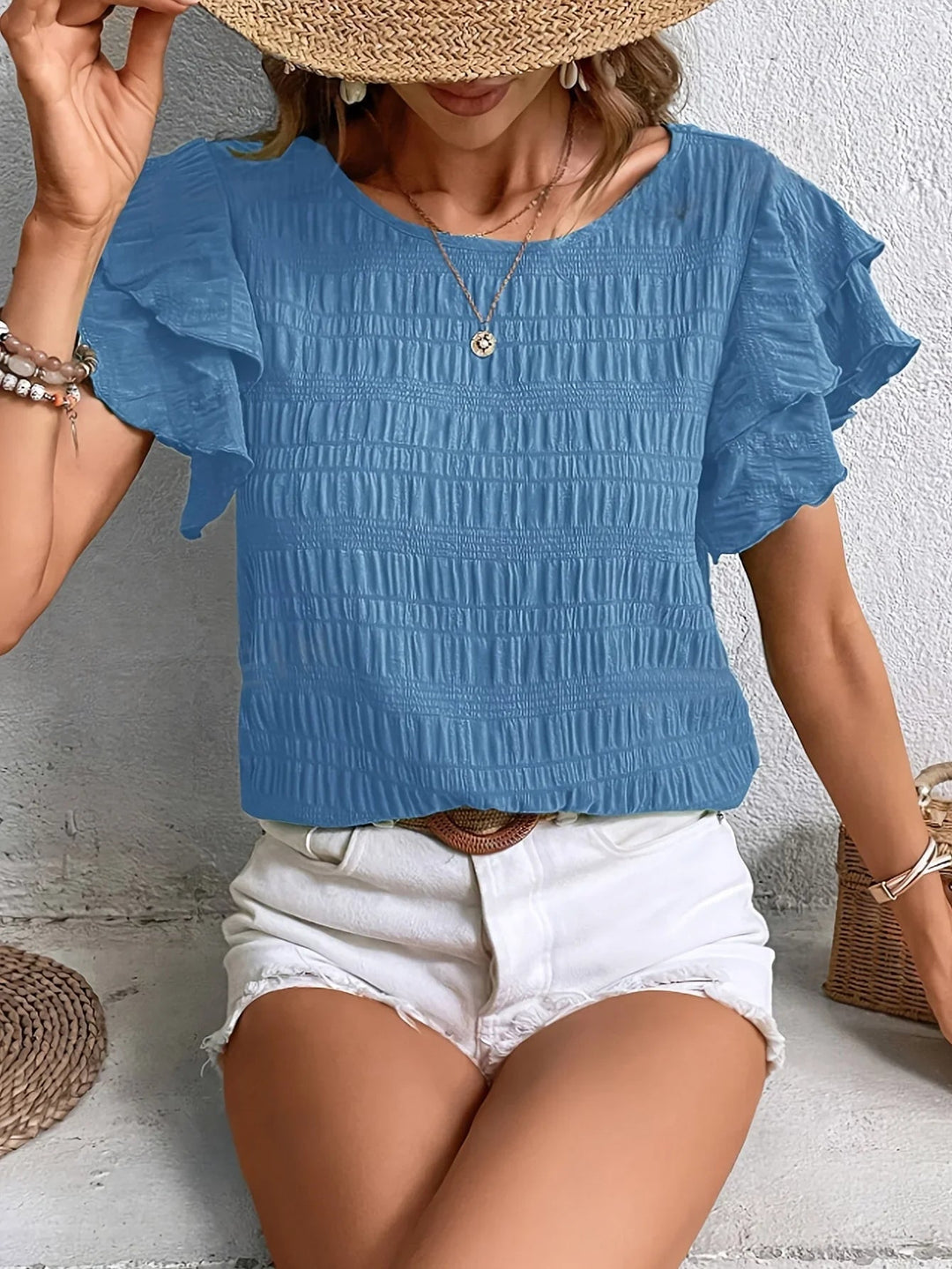 Flatlay of ruffle sleeve blouse in green showing fabric texture and pleat detail