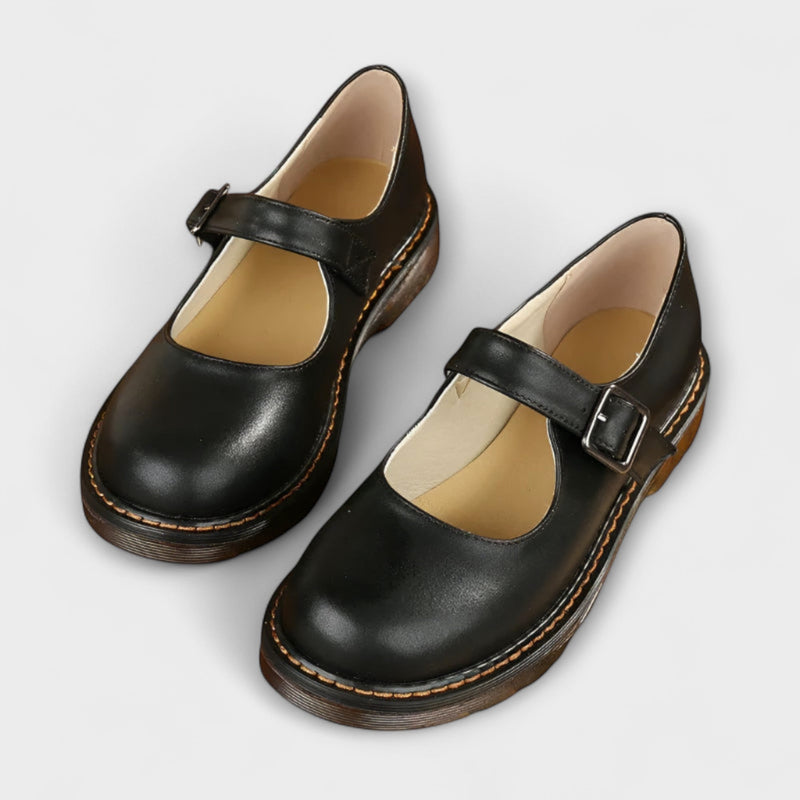 Women's black Mary Jane flat with copper buckle strap and rounded toe, side view