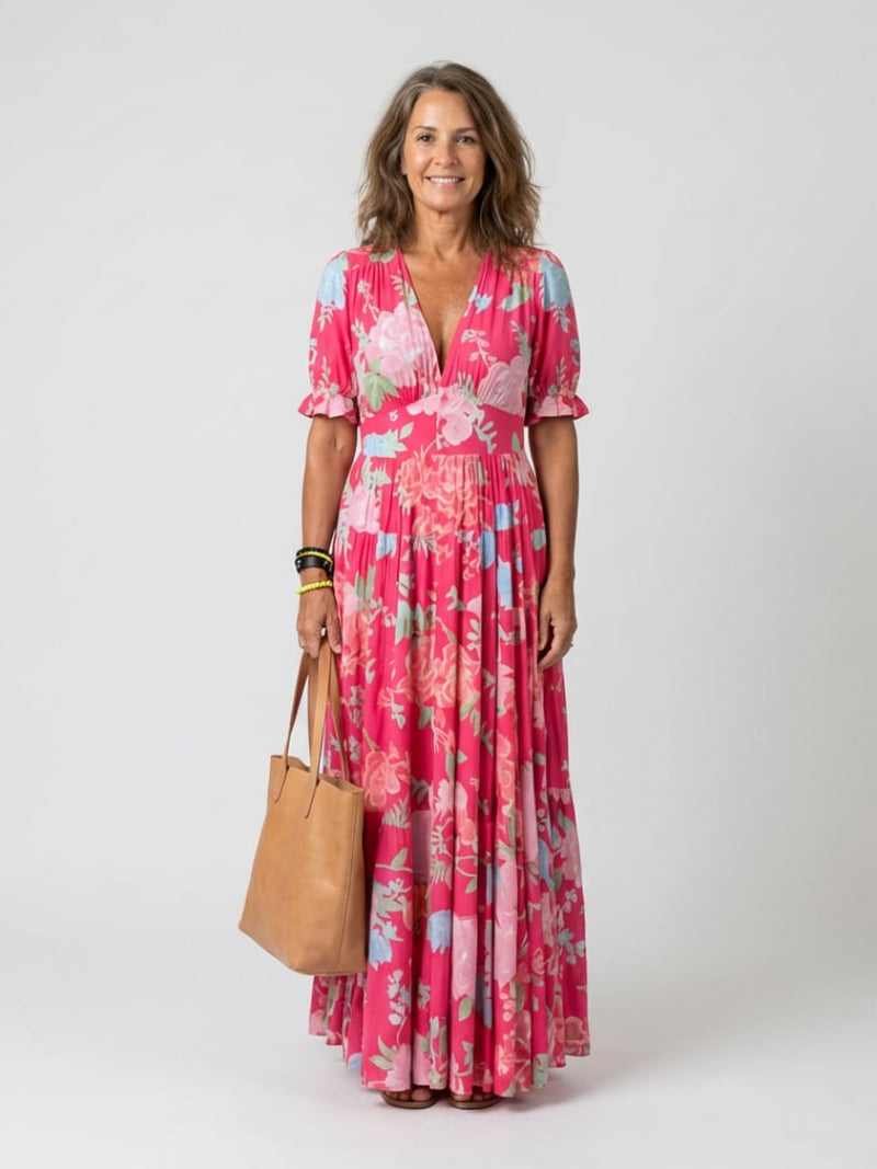 Woman wearing the Dahlia floral V-neck midi dress in pink with a tiered skirt and flutter sleeves