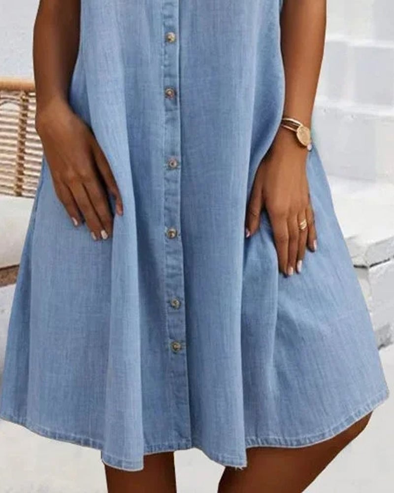 Dark blue denim-look dress worn by a model in a relaxed outdoor setting