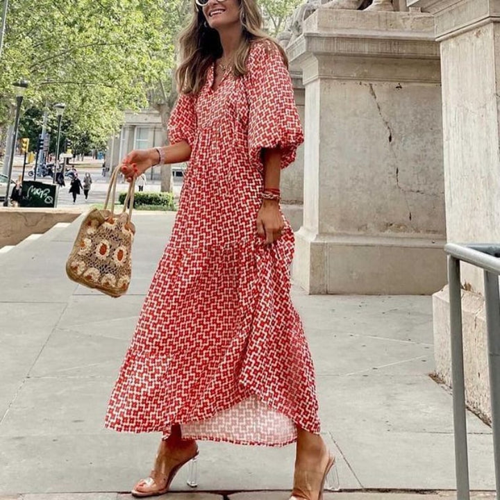 Woman wearing the Flora boho maxi dress in red with geometric print, puff sleeves, and V-neck tie detail