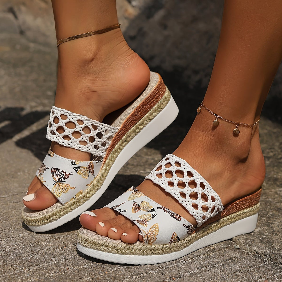Freya woven wedge sandals in black worn on feet, lifestyle shot