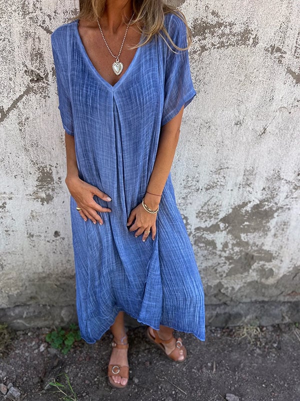 Model wearing blue draped maxi dress styled with strappy heeled sandals