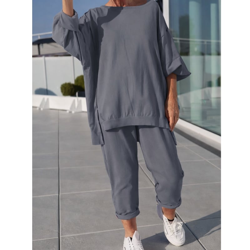 Side view of a woman in the Gilda two-piece loungewear set in gray highlighting the draped fit