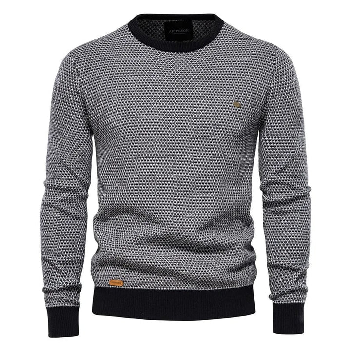 Close-up of checkered pattern and ribbed hem detail on a men's knit sweater