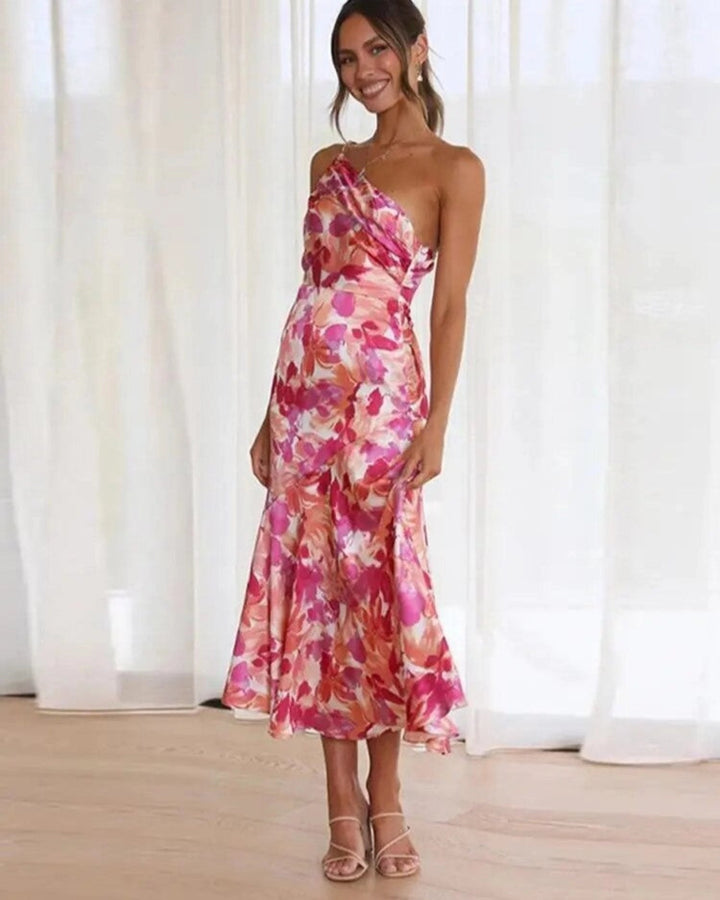Woman wearing an orange floral one-shoulder maxi dress with an asymmetrical hem, front view