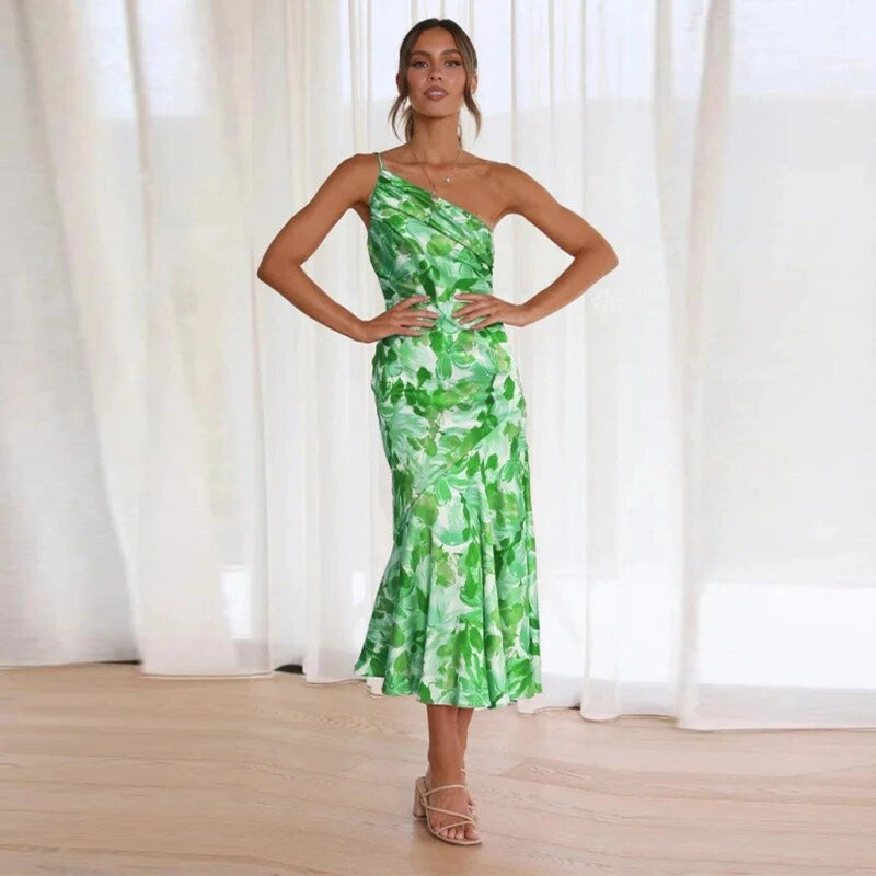 Woman in a pink floral one-shoulder maxi dress standing outdoors, full-length view