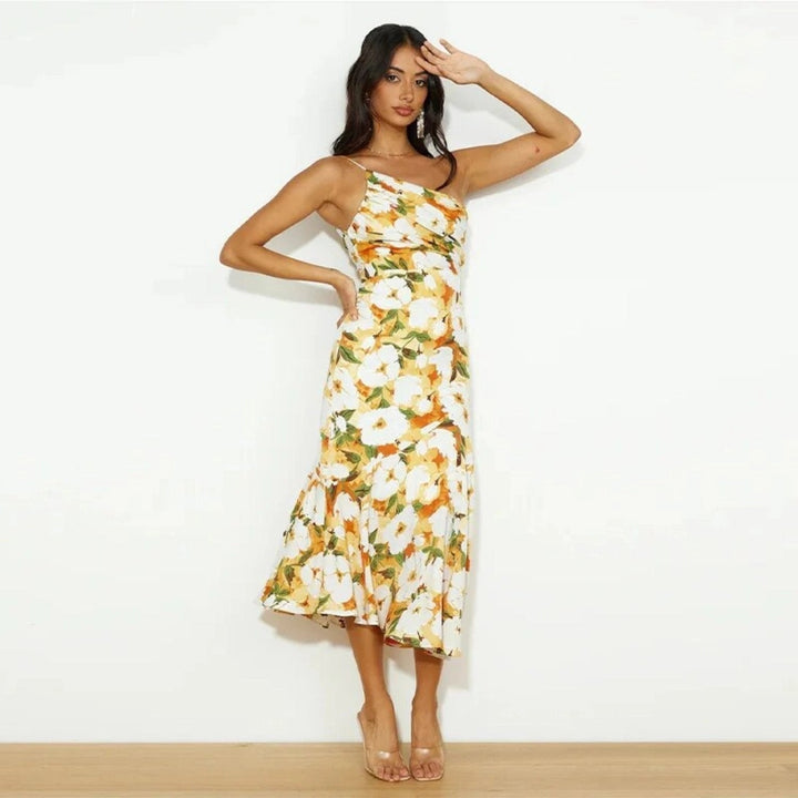 Woman wearing a green floral one-shoulder maxi dress, smiling in natural light