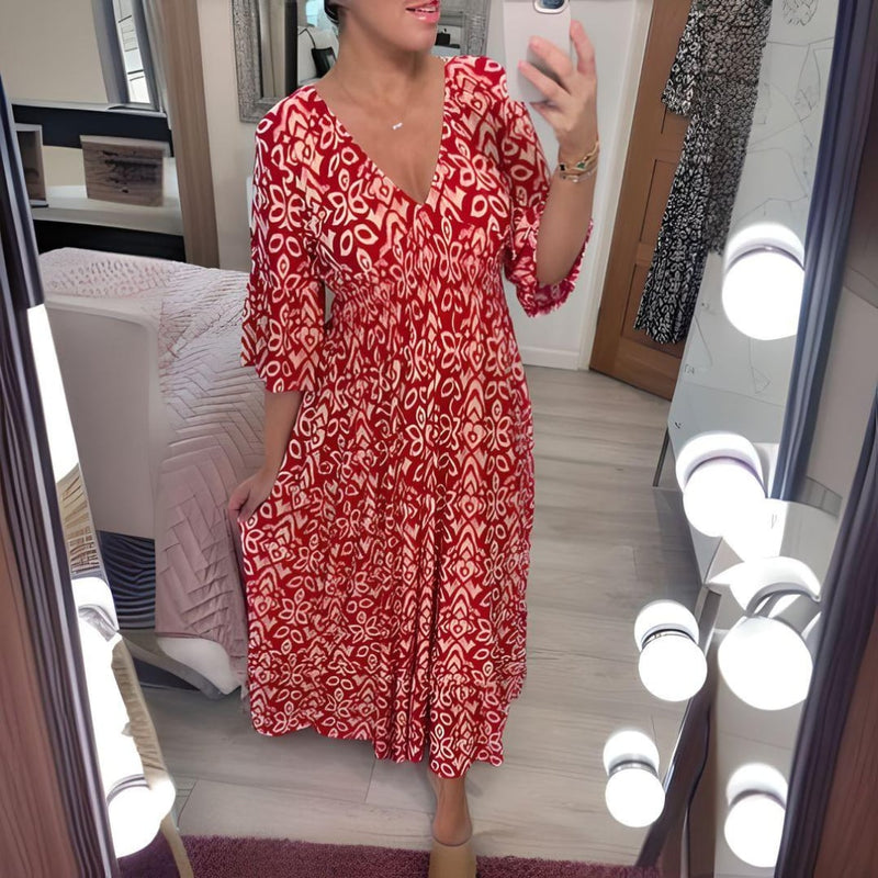 Woman wearing the Lennox flowy tummy control maxi dress in red with flare sleeves on a sunny beach