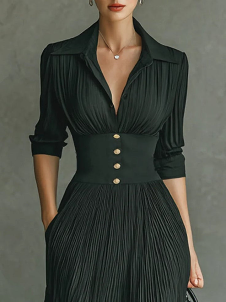 Close-up of pleated skirt detail and belted waist on black long-sleeve maxi dress