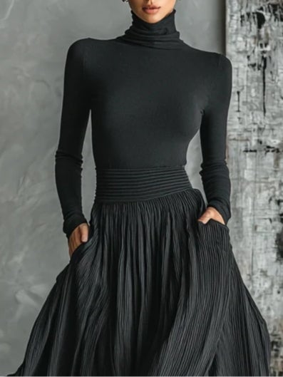 Side view of the black turtleneck and pleated skirt set showing movement and silhouette