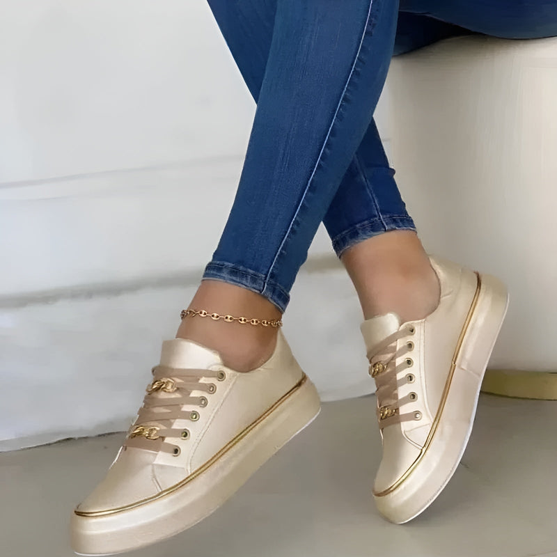 Close-up of gold chain link eyelet hardware and lavender semi-sheer ribbon laces on white sneaker upper