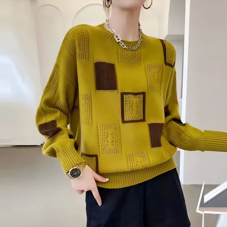 Woman in white patchwork sweater posing in a cozy winter setting
