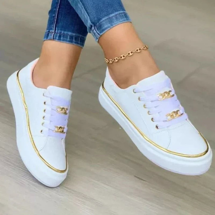 Side view of black lace-up platform sneakers with decorative gold chain accent and metallic gold sole edge