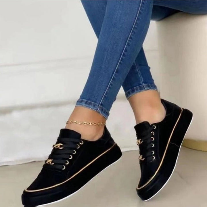 Back view of black women's platform sneakers showing gold-trimmed chunky sole and clean black upper