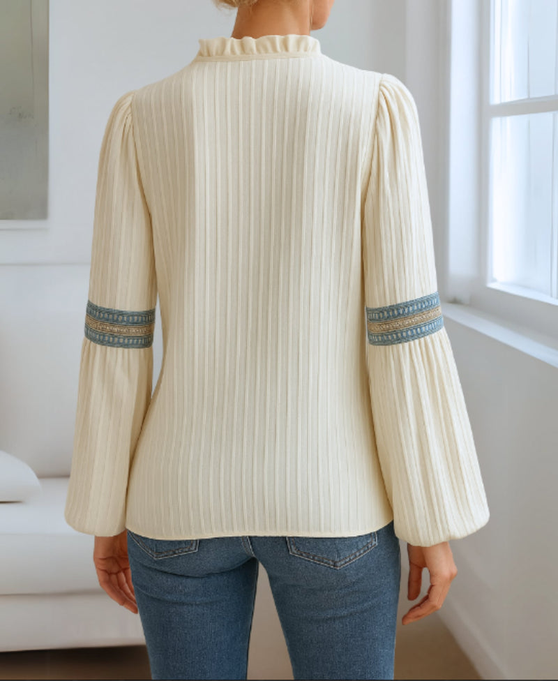 Close-up of delicate vintage-style embroidery on the V-neckline of a flowing blouse