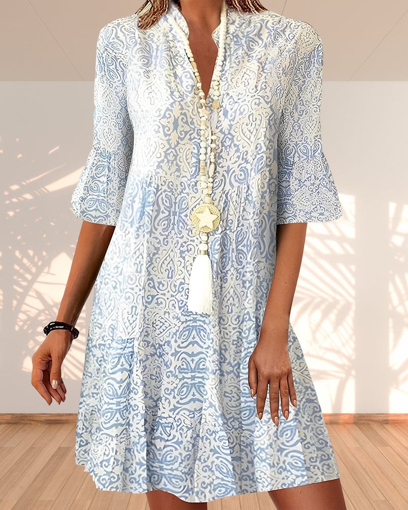 Woman wearing a blue and white paisley printed swing dress with a V-neckline and 3/4 flare sleeves, front view