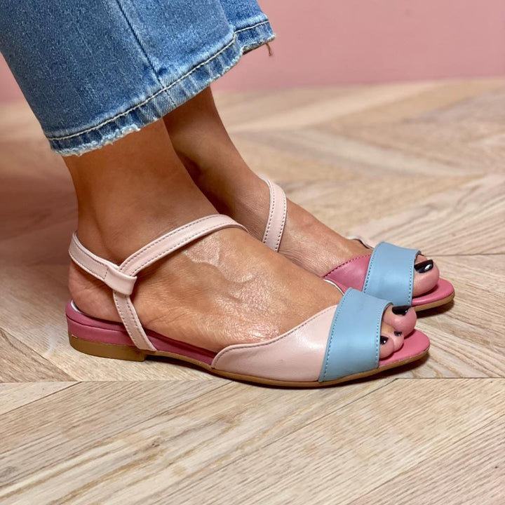 Ophelia pink flat sandals styled on feet, showcasing chic asymmetrical strap design