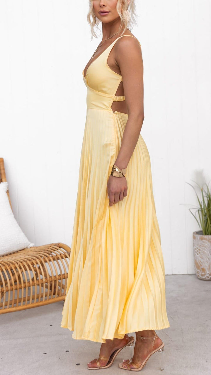 Side view of a woman in a yellow pleated maxi dress showing the fluid, airy skirt movement