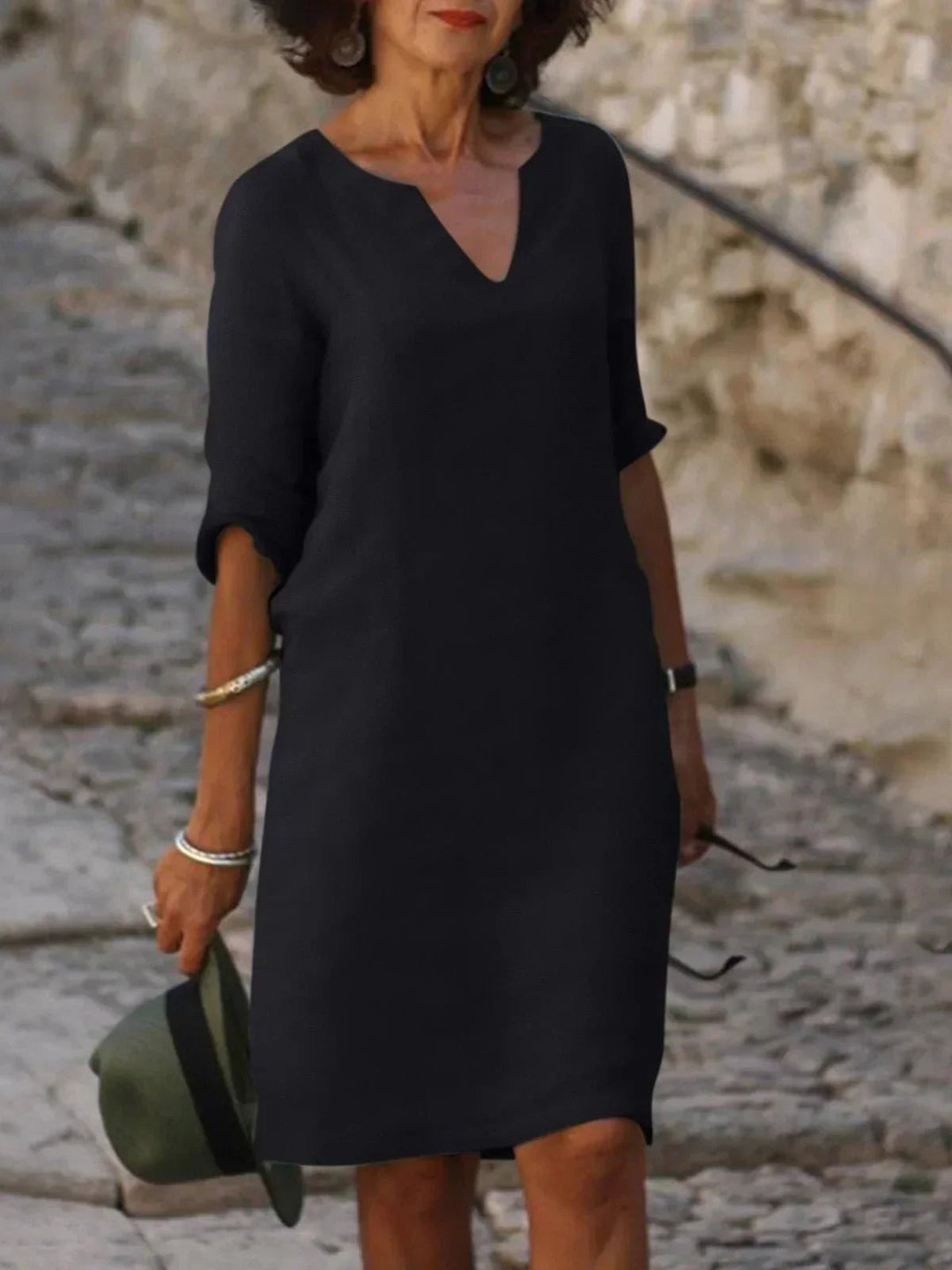 Front view of a flowing V-neck dress in olive green with delicate pleats at the waist