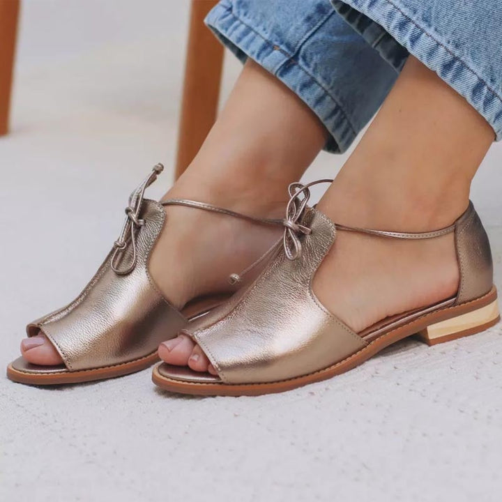 Close-up of the adjustable bow strap and cushioned footbed on the Stella metallic sandal in gold