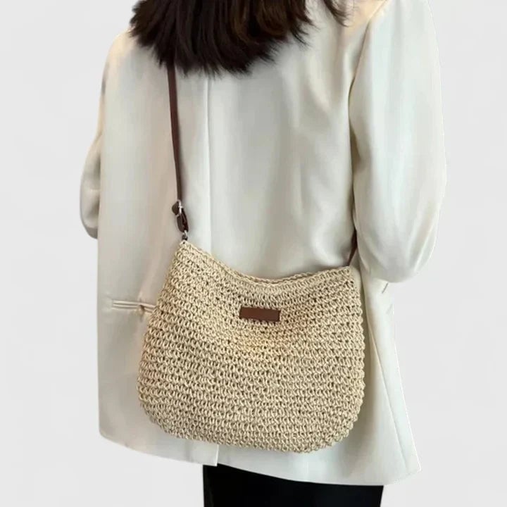 Model carrying the natural shoulder bag in beige over one shoulder outdoors