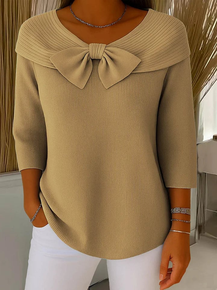 Woman styling a beige bow-accent knit sweater tucked into high-waisted trousers, polished everyday look