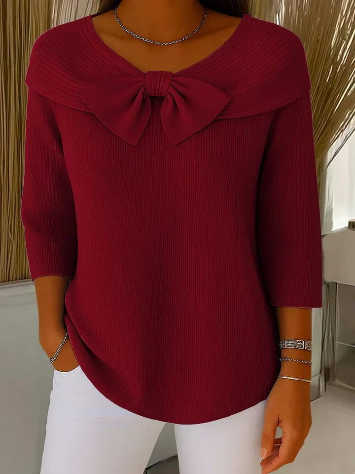 Woman wearing a maroon bow-accent sweater paired with jeans, casual weekend outfit