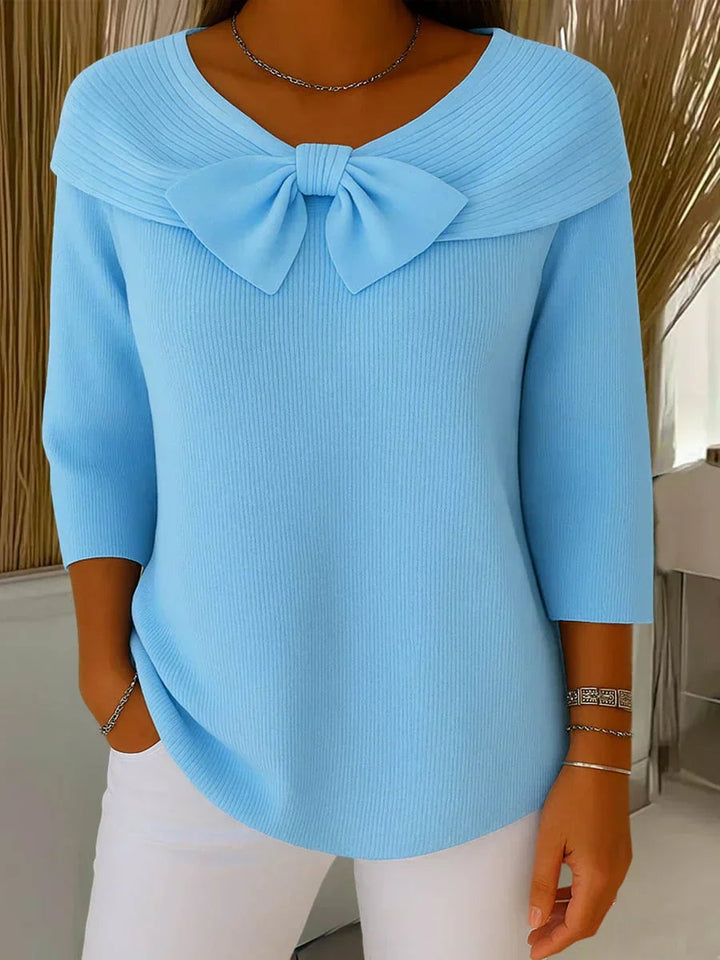 Side profile of a woman in a soft pink bow-accent sweater, showcasing the flattering drape and feminine silhouette