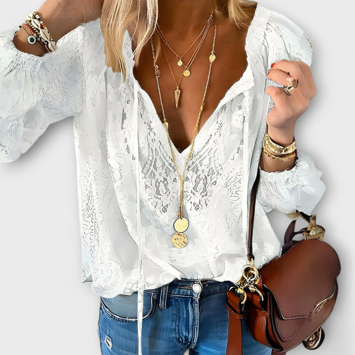Woman wearing the Zeleste white lace V-neck boho blouse with billowy long sleeves and gathered cuffs